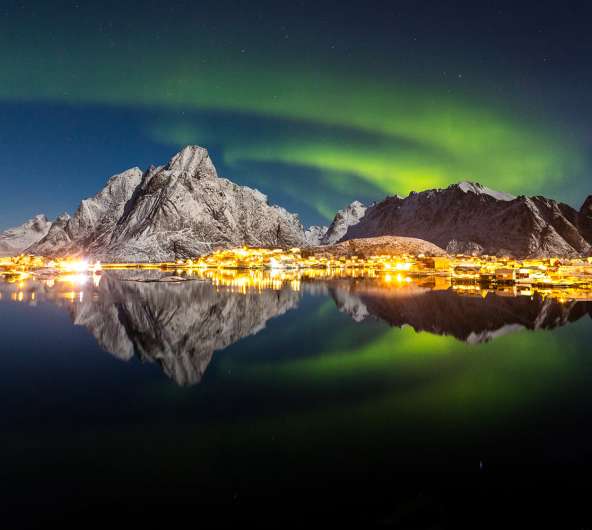 The northern lights over the fishing village Reine in Lofoten, Northern Norway
