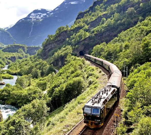 The Flåm Railway going through the landscape of green hills and spectacular mountains in Fjord Norway
