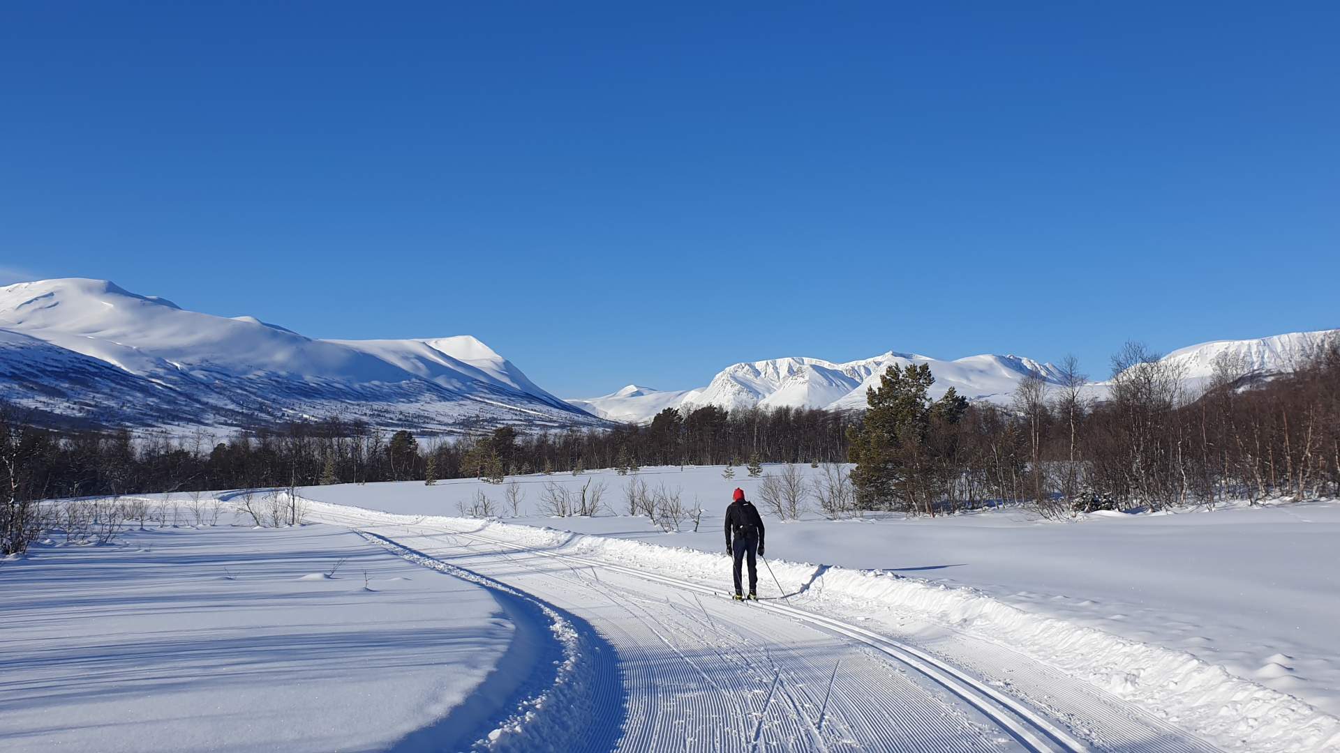 En mann står på ski med et vakkert vinterlandskap med fjell-2024