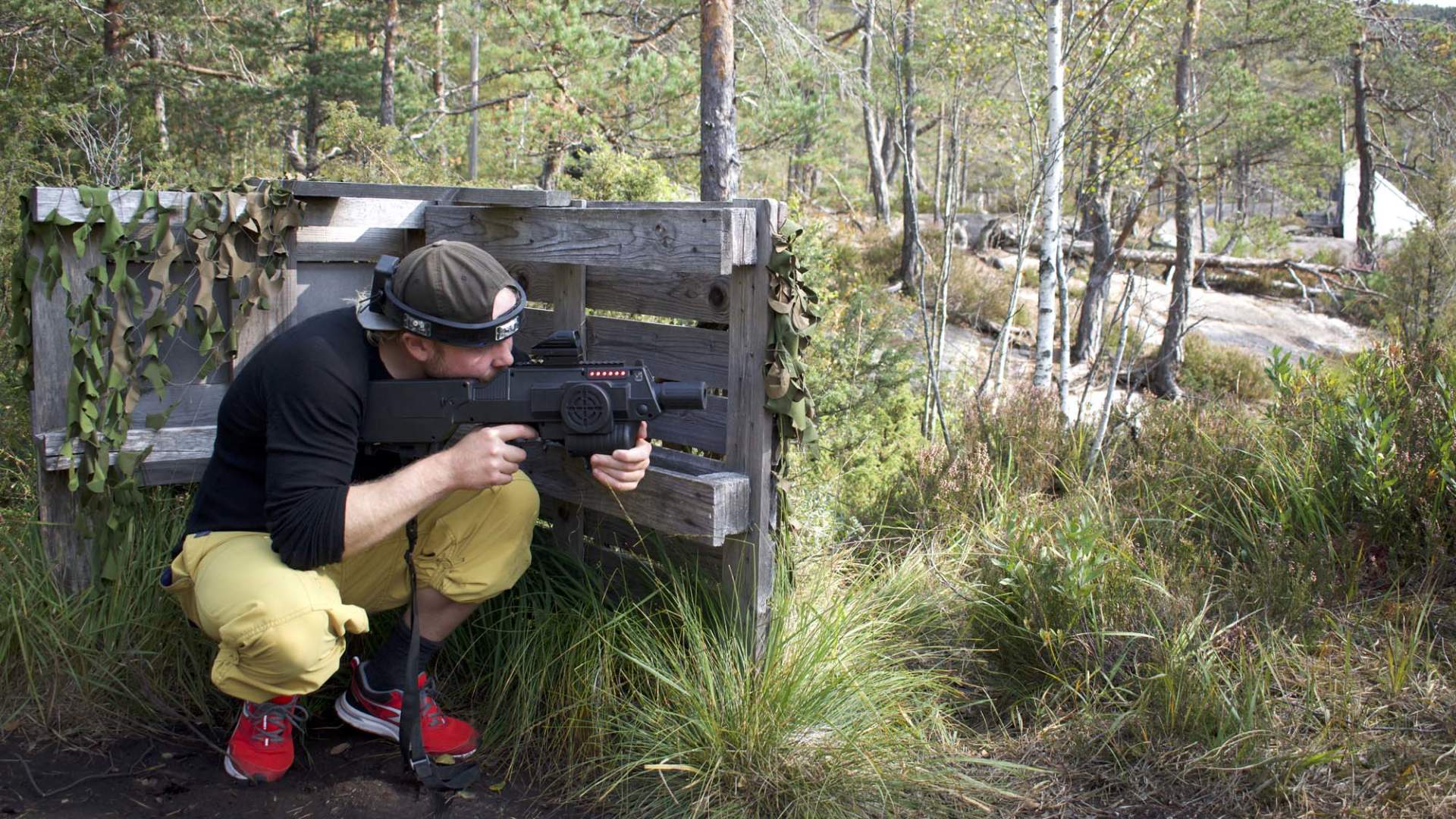 Laser tag deltaker gjemmer seg bak gjerde
