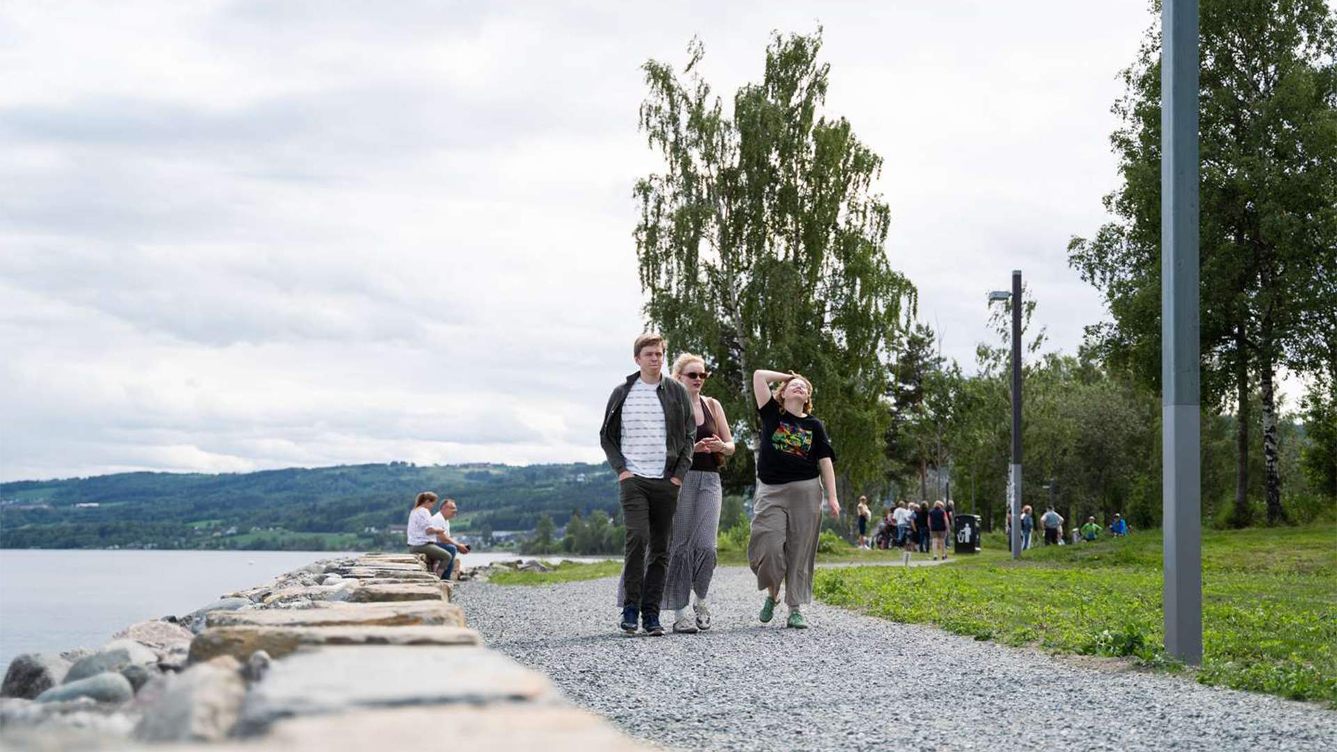 Ungdommer går tur ved stolpemonolitten langs Mjøspromenaden