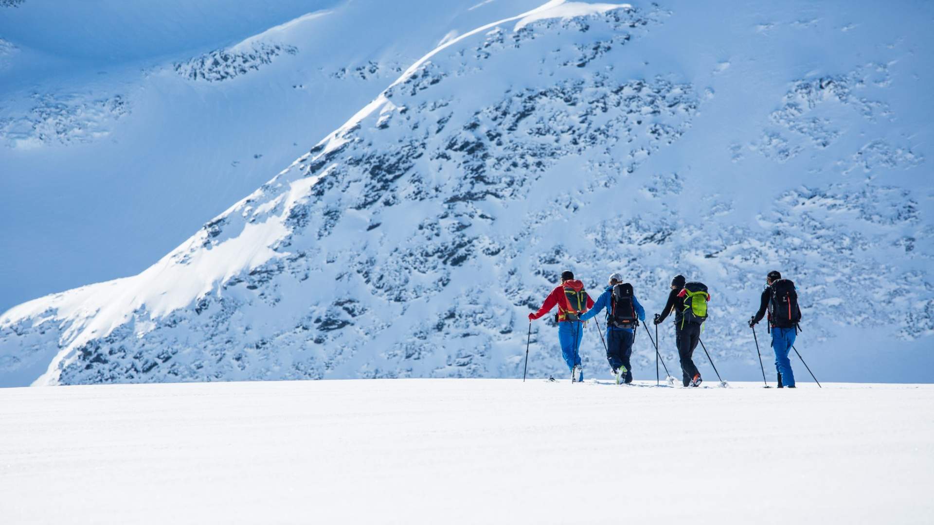 Fire skigåere på topptur i hvit fjellandskap