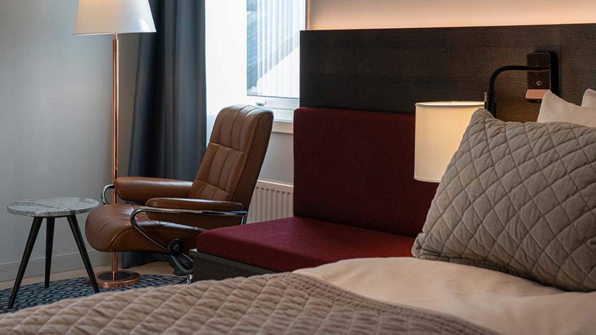 Seng og sitteplass på hotellrommet.