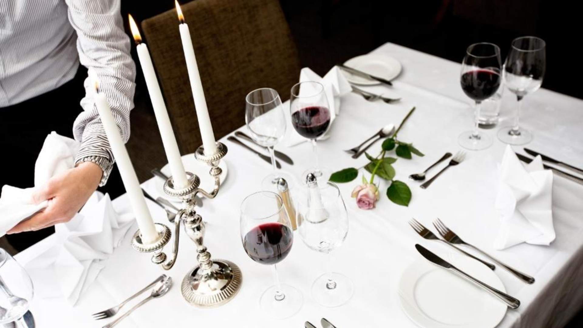 table at restaurant with glasses and candles and a rose