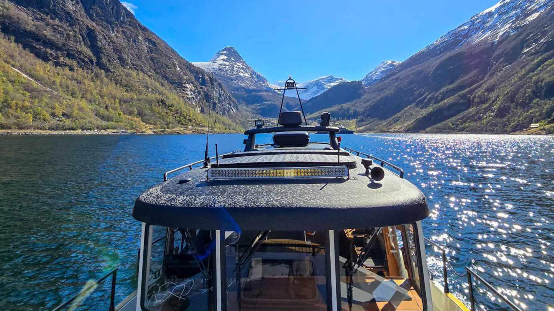 Båten ligger fint i Geirangerfjorden med Geiranger i bakgrunnen.