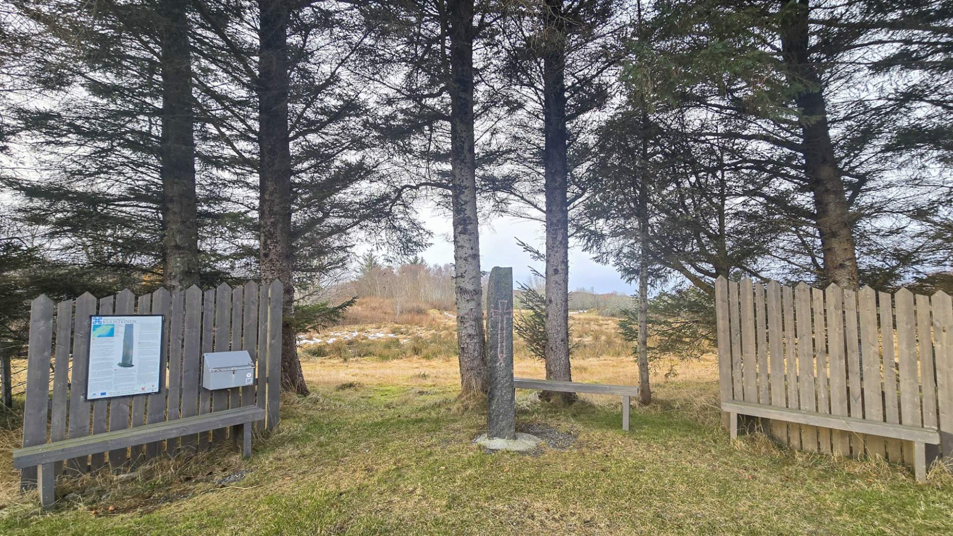 Kulisteinen på Smøla, 2 benker med steinen i midten.