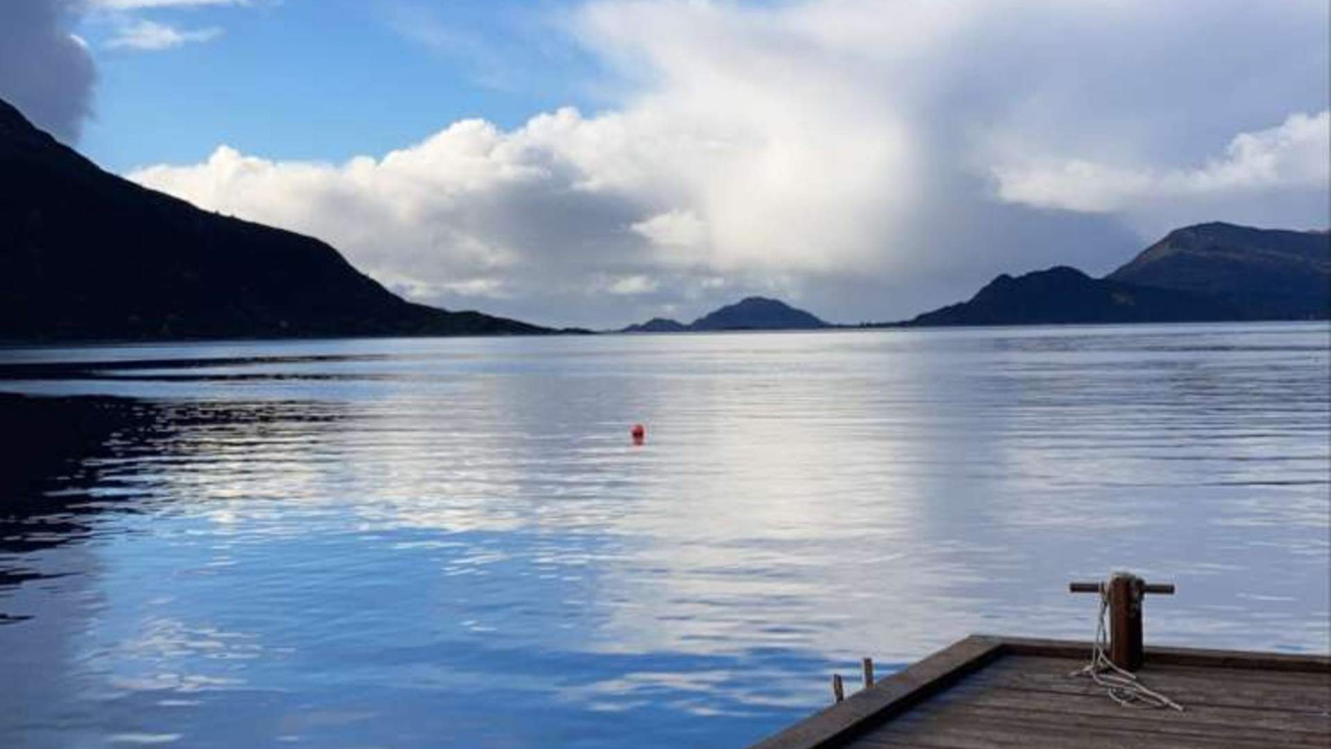 Frå brygga ser du utover sjøen, fjella og øyane.