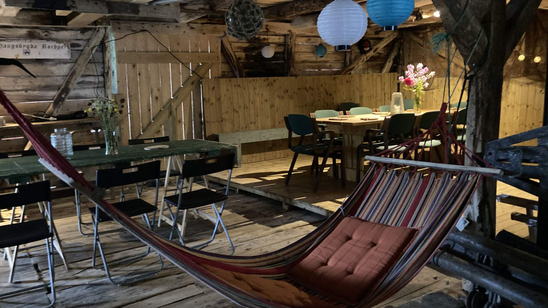 Kosleg fellesrom i rorbua med langbord og sittesoner med hengekøye.