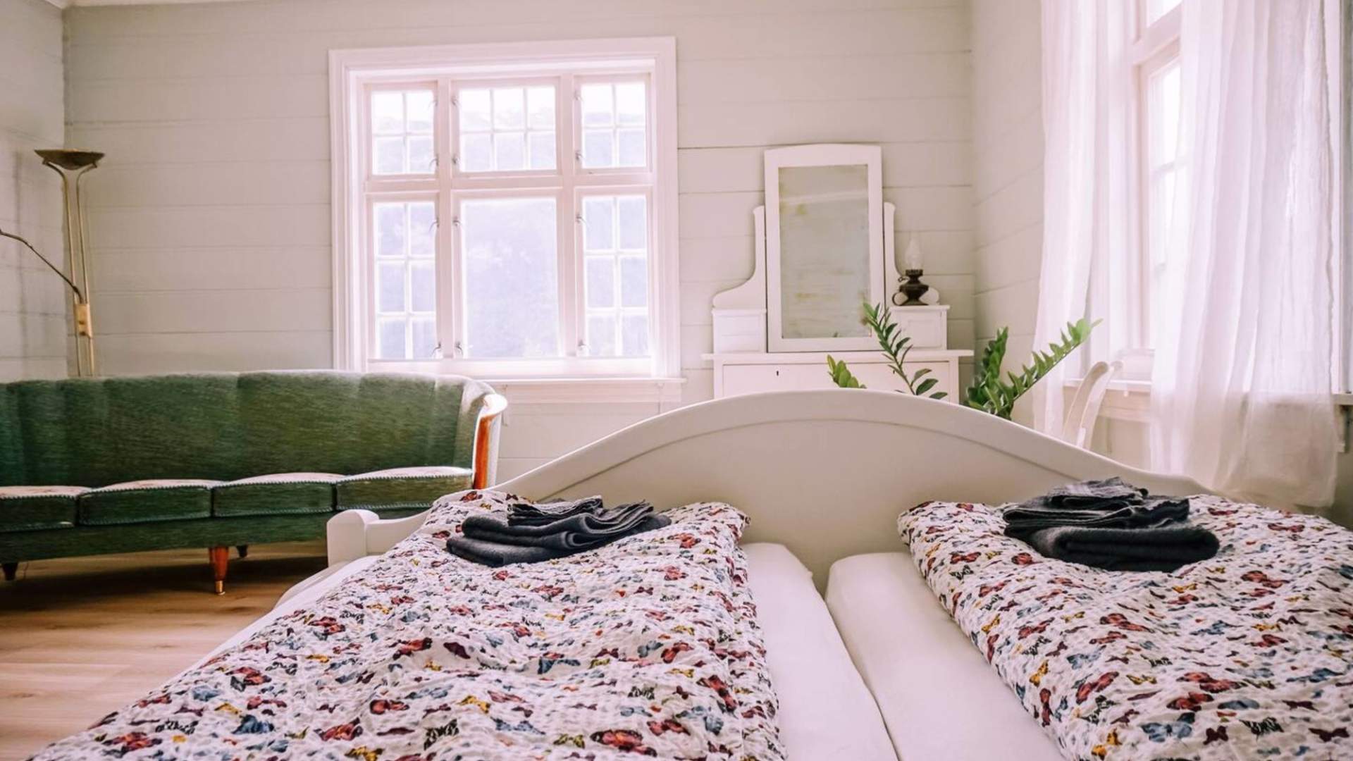 Romslig soverom med sofa og store vindu.