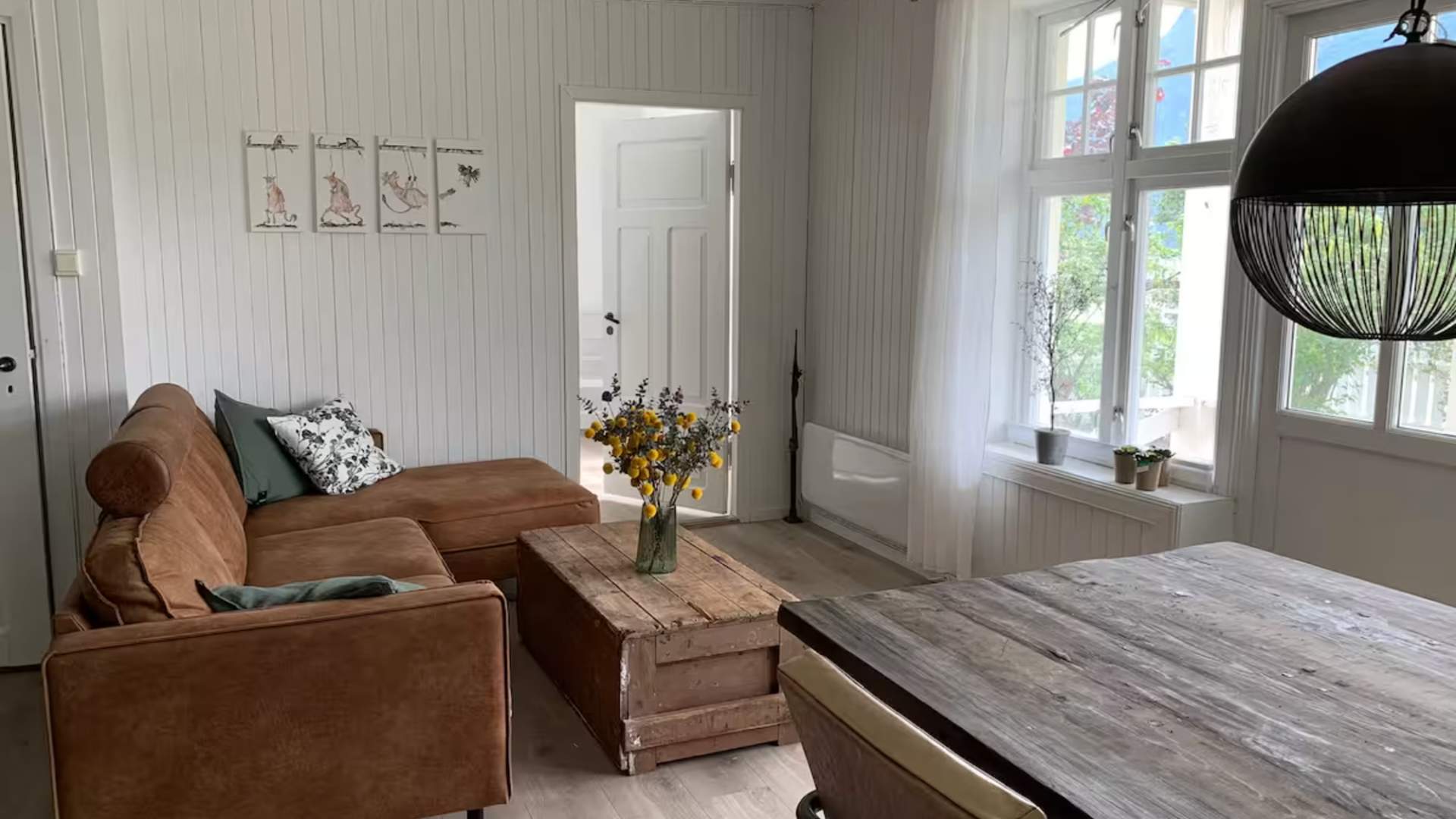 Koslig stue med sofagruppe og utsikt mot fjorden.