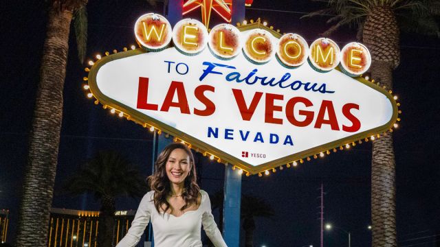 A woman posing happily in front of the famous "Welcome to Fabulous Las Vegas Sign".