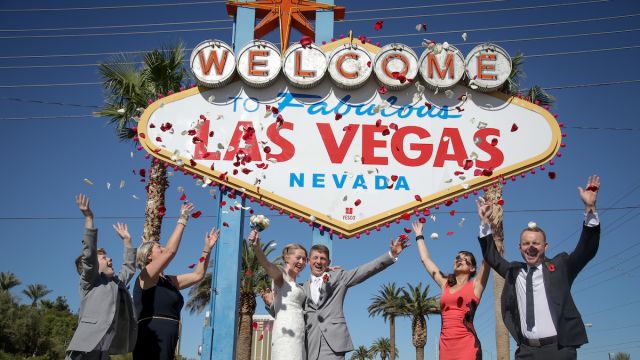A group celebrating a wedding outside of the famous Las Vegas sign.