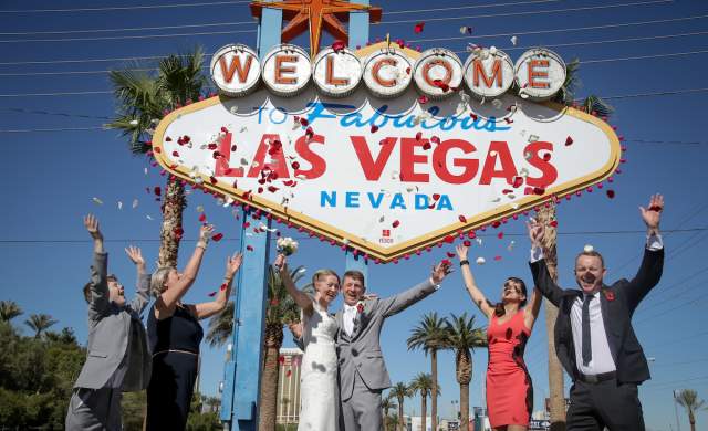 A group celebrating a wedding outside of the famous Las Vegas sign.