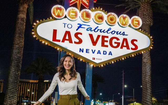A woman posing happily in front of the famous "Welcome to Fabulous Las Vegas Sign".
