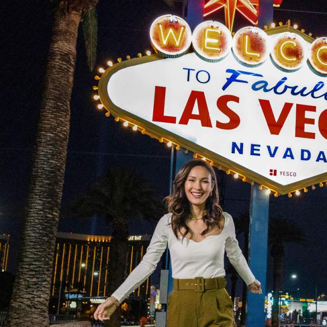 A woman posing happily in front of the famous "Welcome to Fabulous Las Vegas Sign".