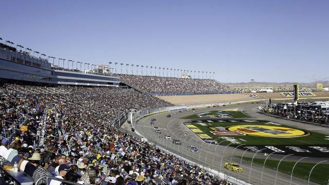 A race going on at the Las Vegas Motor Speedway with a roaring crowd.
