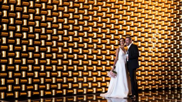 A couple standing in front of a wall for a wedding photo.