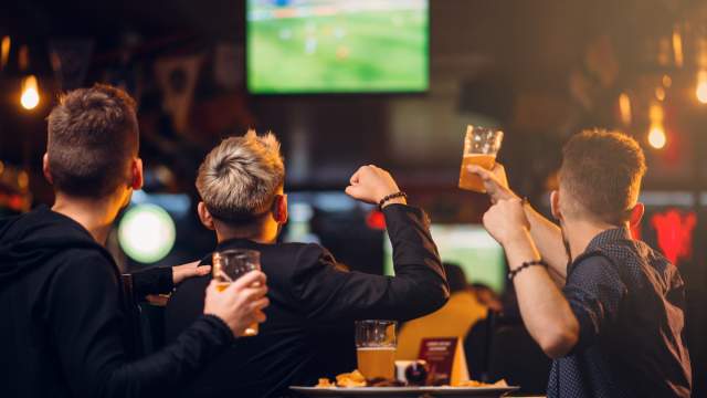 A table of excited sports fan cheering on their team with beers in hand!