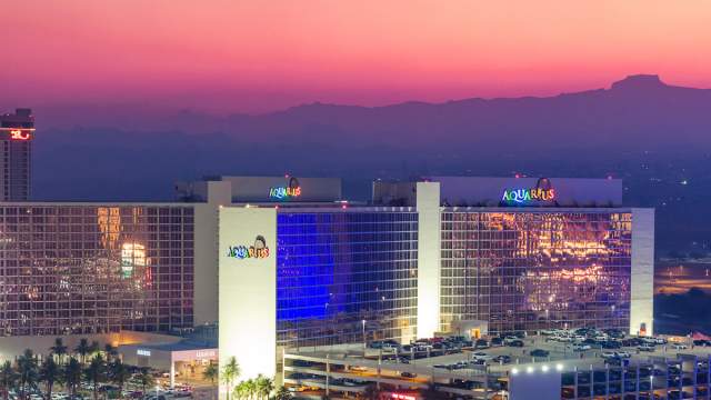Exterior view of Aquarius Casino Resort with a beautiful sunset across the surrounding mountains.