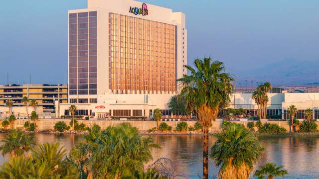 Exterior view of Aquarius Casino Resort with lush landscape and the Colorado River.