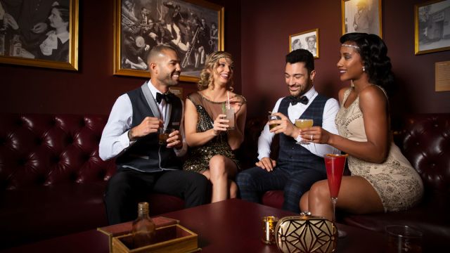 A group of people enjoying themselves with a drink at The Underground Speakeasy inside of the Mob Museum.