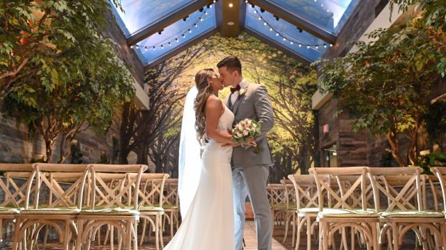Wedding photo of a newly wed couple kissing at the Glass Garden in Chapel of the Flowers