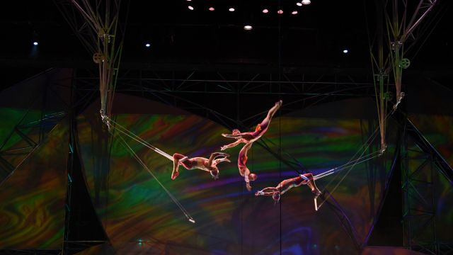 A group of performers doing trapeze on stage during the Mystere show by Cirque du Soleil.