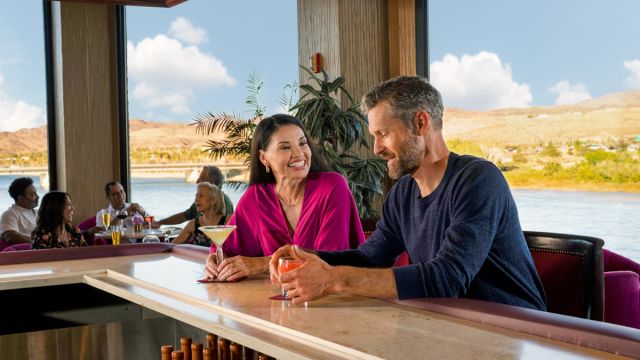 A couple enjoying some delicious cocktails in Laughlin with the beautiful Colorado river behind them.