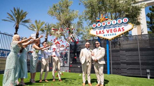 Couple celebrating wedding in front of the iconic "Married in Fabulous Las Vegas" sign at Chapel of the Flowers