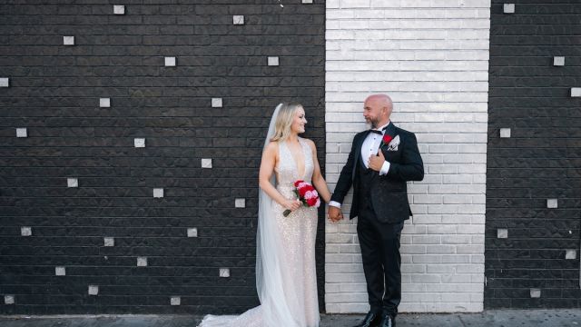 Couple posing in front of a black and white wall for wedding