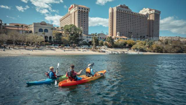 People kayaking in the Colorado River in Laughlin, Nevada with casinos in the background.