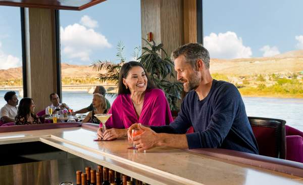A couple enjoying some delicious cocktails in Laughlin with the beautiful Colorado river behind them.