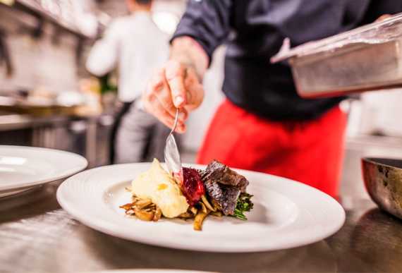 En kokk anretter mat på en restaurant i Bergen