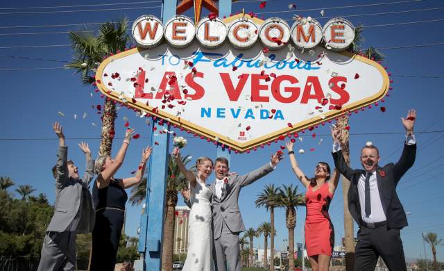 A group celebrating a wedding outside of the famous Las Vegas sign.