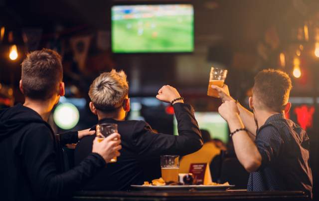 A table of excited sports fan cheering on their team with beers in hand!