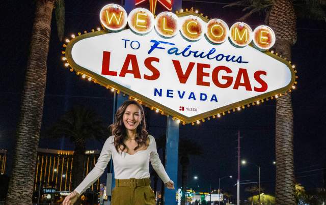 A woman posing happily in front of the famous "Welcome to Fabulous Las Vegas Sign".