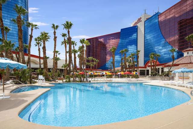Outdoor pool at Rio Las Vegas surrounded by pool deck with lounge chairs and palm trees.