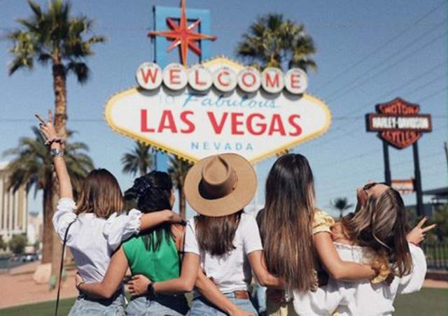 group of girls standing in front of welcome to las vegas sign