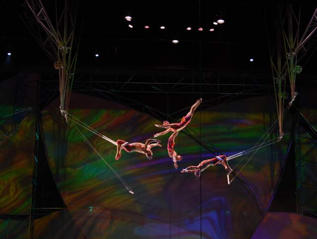 A group of performers doing trapeze on stage during the Mystere show by Cirque du Soleil.