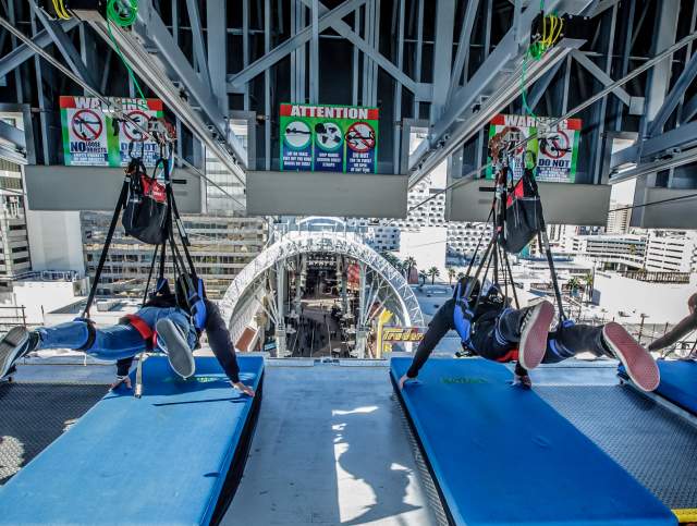 Two people in zipline harnesses laying down waiting for the ride to start