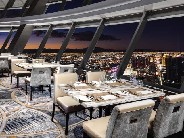 Interior of the Top of the World restaurant at The STRAT with a view of the city lights with a sunset in the background. PHOTO CREDIT ANTHONY MAIR