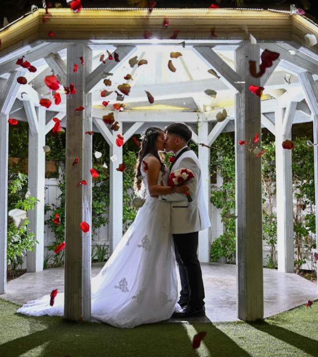 Newly wed couple sharing a kiss under a canopy at Chapel of the Flowers