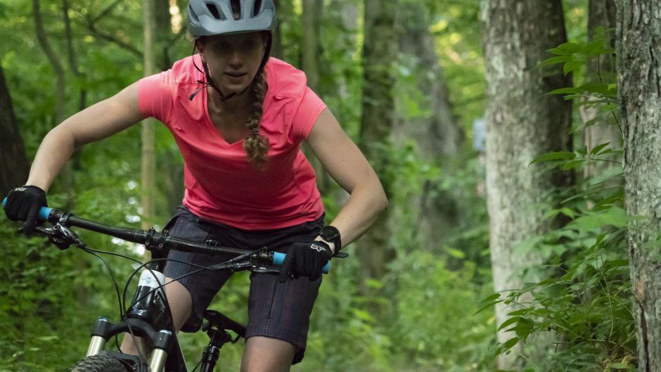 Mountain biker with pink shirt riding through a trail near Grand Rapids
