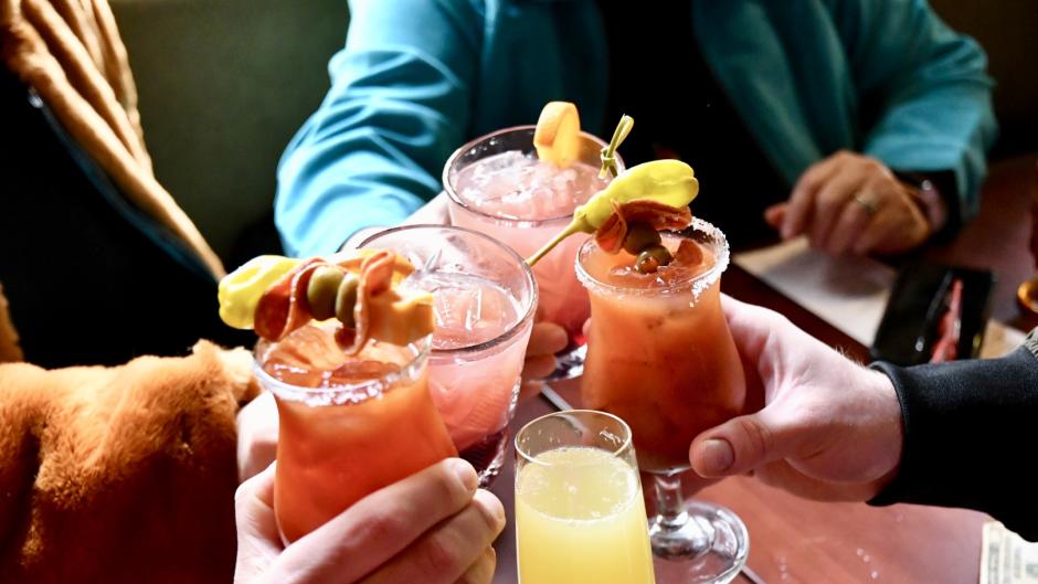 Friends with cocktails cheers during Drag Brunch in Grand Rapids