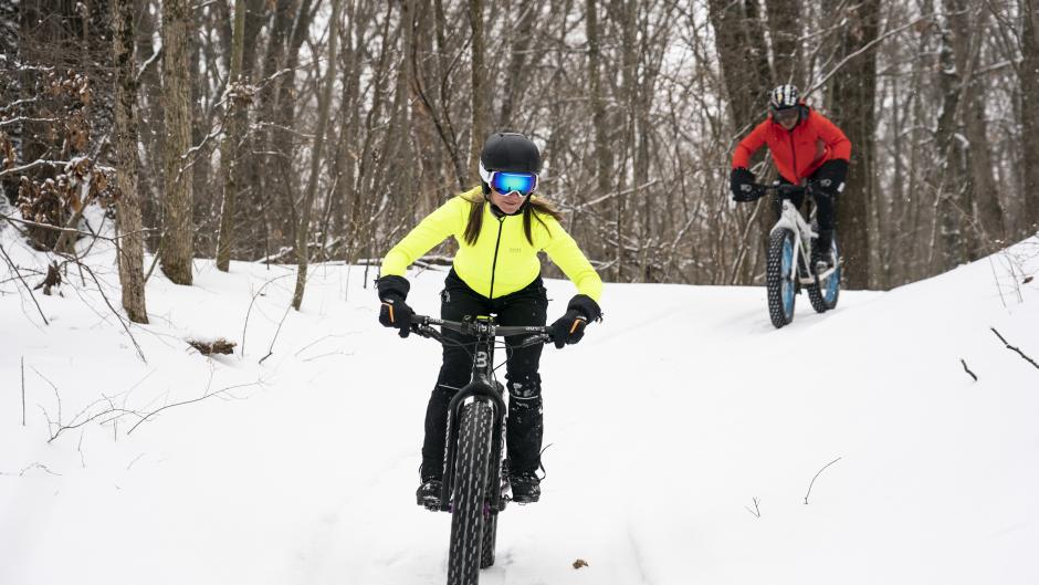 Two people biking through snowy trails