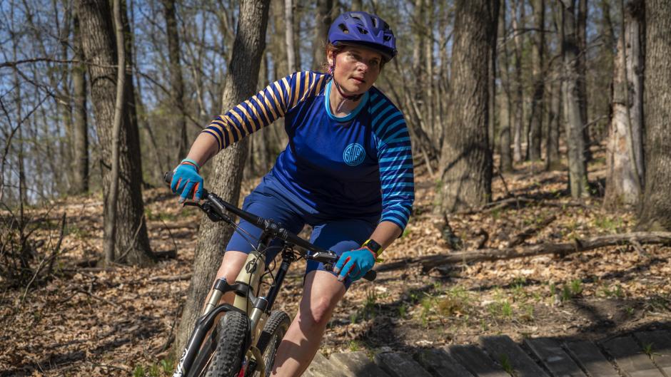 Mountain biker in blue shirt with stripes biking on a trail near Grand Rapids
