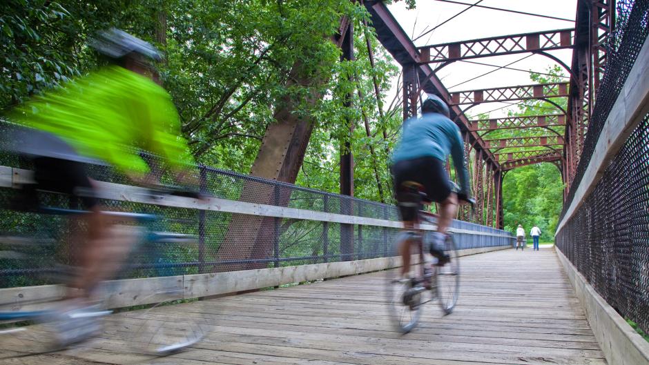 Two People Speeding Across a Bridge on Bikes