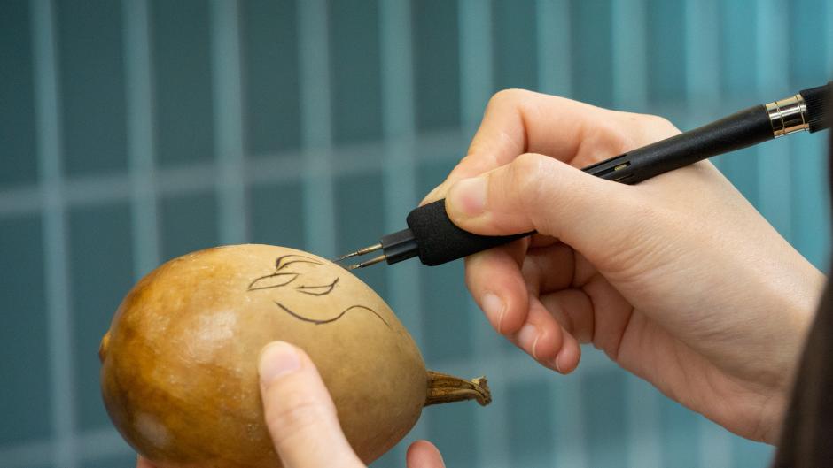Using a wood burning tool on a gourd.