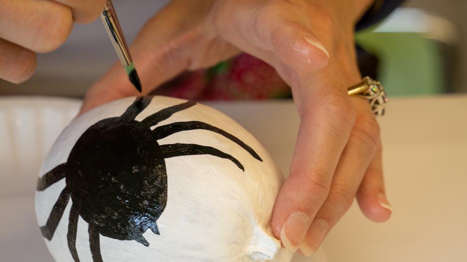 White gourd with a black spider painted on it.