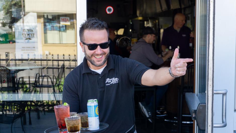 An employee at Putt Putts entering the patio with a drink tray.